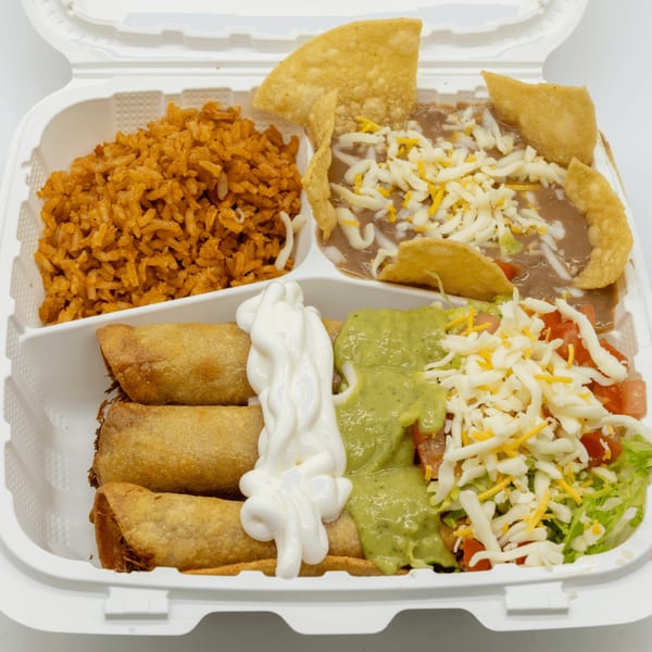 Mexican food in a takeout container with rice, beans, taquitos, guacamole, sour cream, and salad.